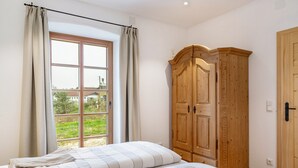 Une chambre avec une grande fenêtre, une armoire en bois et un lit avec une literie à rayures.