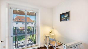 A room with a glass table, white chairs, a window with blinds, a small table with a lamp, and a framed picture on the wall. - Holiday Apartment 'Terrassenwohnung' with Private Terrace and Wi-Fi (Rötha)