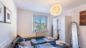A bedroom with two beds, a window, a radiator, a wardrobe, and a mirror. - Holiday Apartment 'Terrassenwohnung' with Private Terrace and Wi-Fi (Rötha)