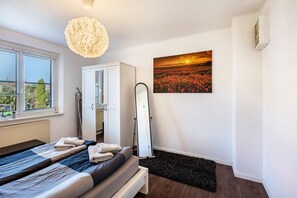 Camera da letto con un letto, un'armadio bianco, uno specchio, un quadro raffigurante un tramonto e un termosifone.