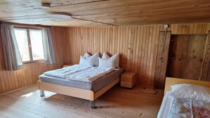 A wooden-paneled room with a bed, a nightstand, and a window. - Apartment 'Ferienwohnung in Altem Bauernhaus' with Mountain View, Private Garden and Wi-Fi (Schwarzenberg)