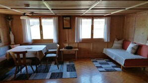 A wooden interior with a dining table, a sofa, a chair, and a small desk. - Apartment 'Ferienwohnung in Altem Bauernhaus' with Mountain View, Private Garden and Wi-Fi (Schwarzenberg)