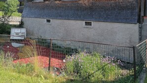 A two-story building with a wooden facade, multiple windows with shutters, and a visible outdoor area with a fence and flowers. - Apartment 'Ferienwohnung in Altem Bauernhaus' with Mountain View, Private Garden and Wi-Fi (Schwarzenberg)