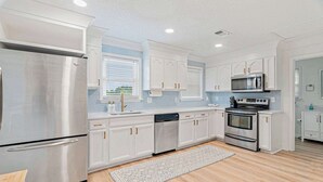 Een moderne keuken met roestvrijstalen apparatuur, witte kasten en een blauwe betegelde achterwand.