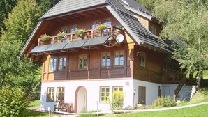 Eine Holzhütte mit Balkon, mehreren Fenstern und einer Treppe, die zu einem oberen Stockwerk führt.