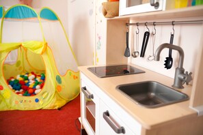 A children's play area with a ball pit and a small kitchen setup including a sink and stove.