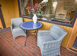 Un set di sedia e tavolino in vimini su un patio in mattoni, con vista su una finestra.