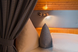 A room with a bed, a patterned pillow, a textured pillow, and a wall with a geometric tile pattern. - Apartment Mattenweg - Appartement 8 - 'Rose' (Hinterzarten)