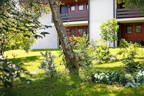 Ein modernes Gebäude mit einem gepflegten Garten, einem Baum und einem kleinen Strauch.