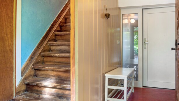 A wooden staircase leading to a room with a white door and a small white table. - Apartment 'Alte Schmiede Ellrichshausen' with Wi-Fi (Satteldorf)