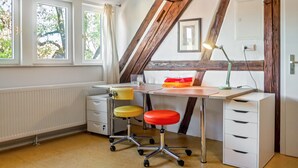 A room with a desk, two chairs, a radiator, and a window with curtains. - Apartment 'Alte Schmiede Ellrichshausen' with Wi-Fi (Satteldorf)