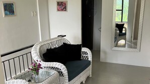 A room with a white wicker sofa, a small table with a vase of flowers, and a mirror on the wall. - Peaceful Valencia Dream Home (Valencia)