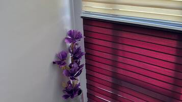 Una escalera con barandilla metálica, pared blanca y una ventana con persianas horizontales.
