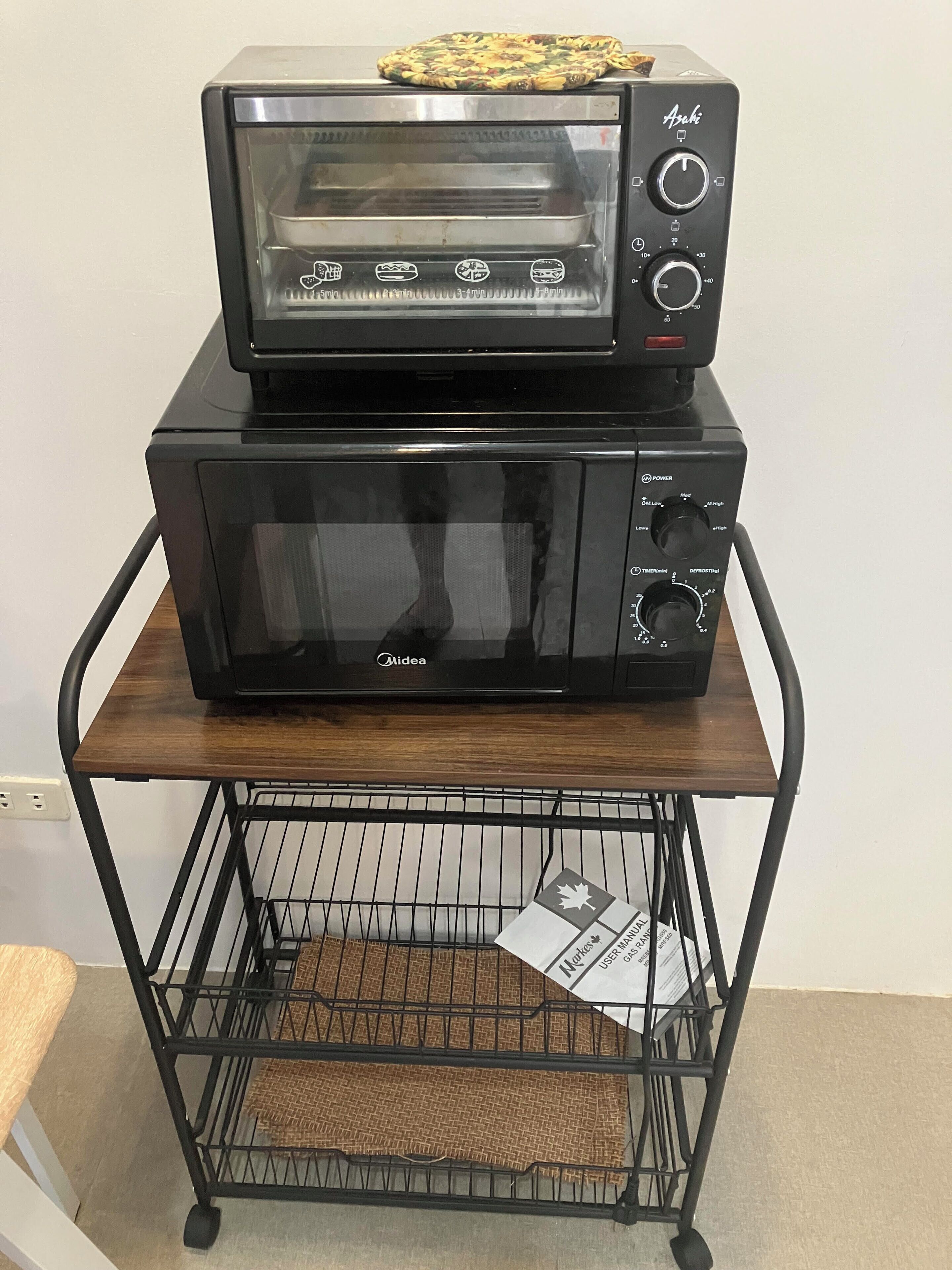 A black Midea microwave oven with a control panel and a black toaster oven on top.