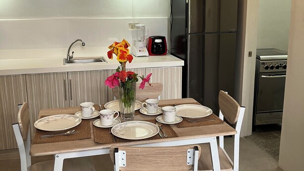 A modern kitchen with white cabinets, a stainless steel refrigerator, a coffee maker, and a dining table set for four. - Peaceful Valencia Dream Home (Valencia)