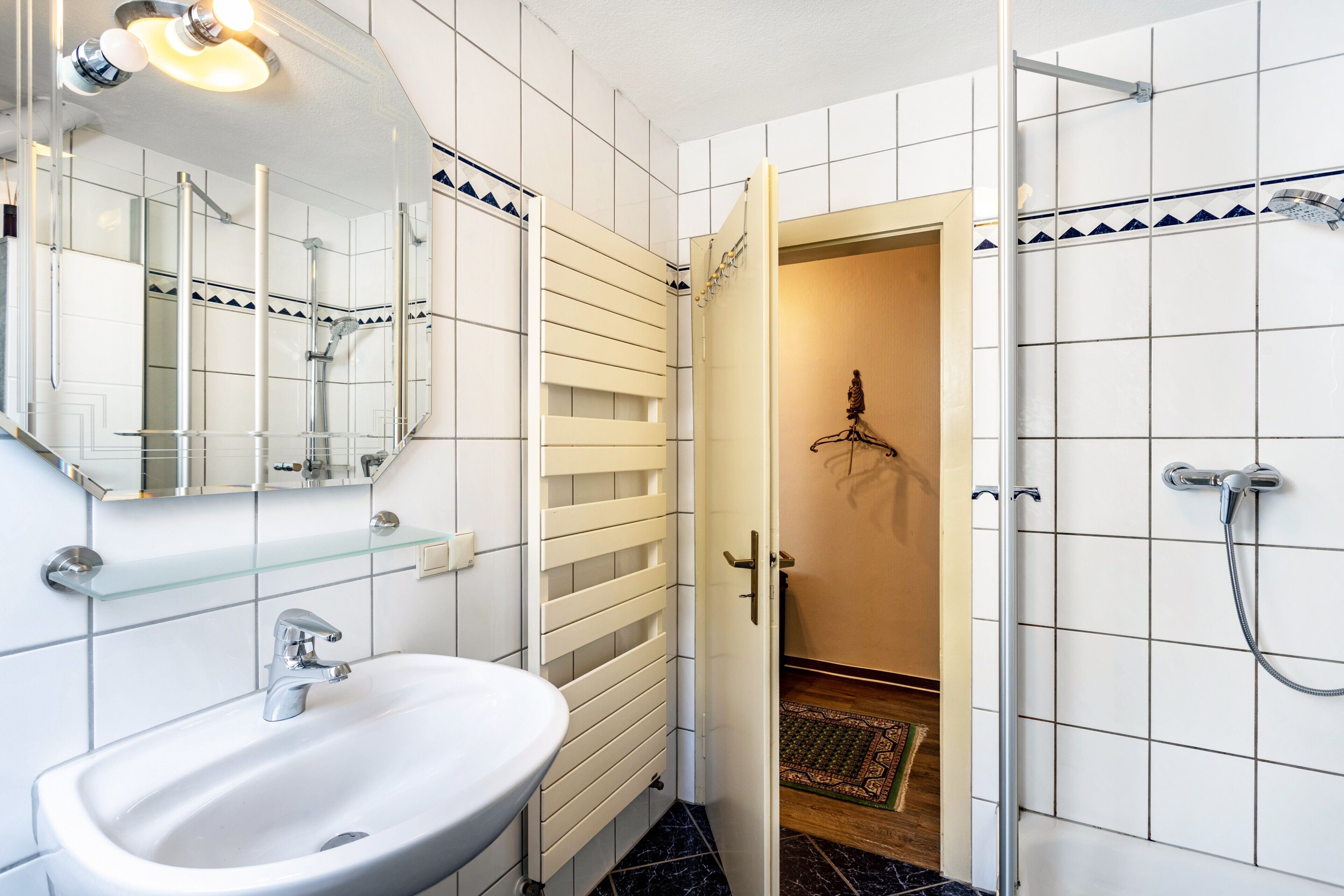 A bathroom with a white sink, mirror, and shower.