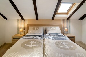 A bedroom with a bed featuring nautical-themed bedding, wooden headboard, and a skylight. - Apartment 'Möwe' with Private Terrace, Garden, and Wi-Fi (Hinte)