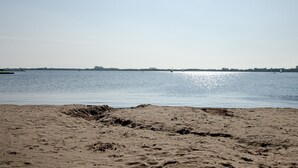 A beach with a clear sky, calm water, and distant shoreline. - Apartment Möwe with Private Terrace, Fenced Garden & Wi-Fi (Hinte)