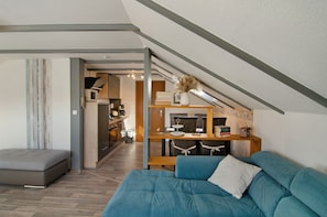 A loft-style room with a high ceiling, a dining area, and a kitchenette. - Apartment 'Möwe' with Private Terrace, Garden, and Wi-Fi (Hinte)