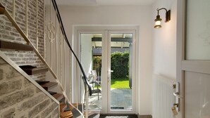 A staircase with a brick wall, a glass door leading outside, and a white radiator. - Apartment Möwe with Private Terrace, Fenced Garden & Wi-Fi (Hinte)