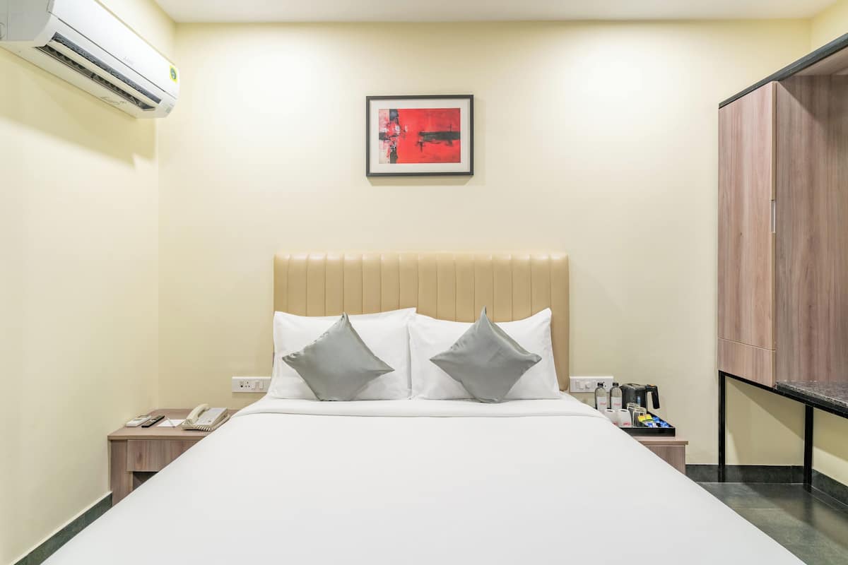 Una habitación de hotel con cama, mesita de noche y un cuadro en la pared.