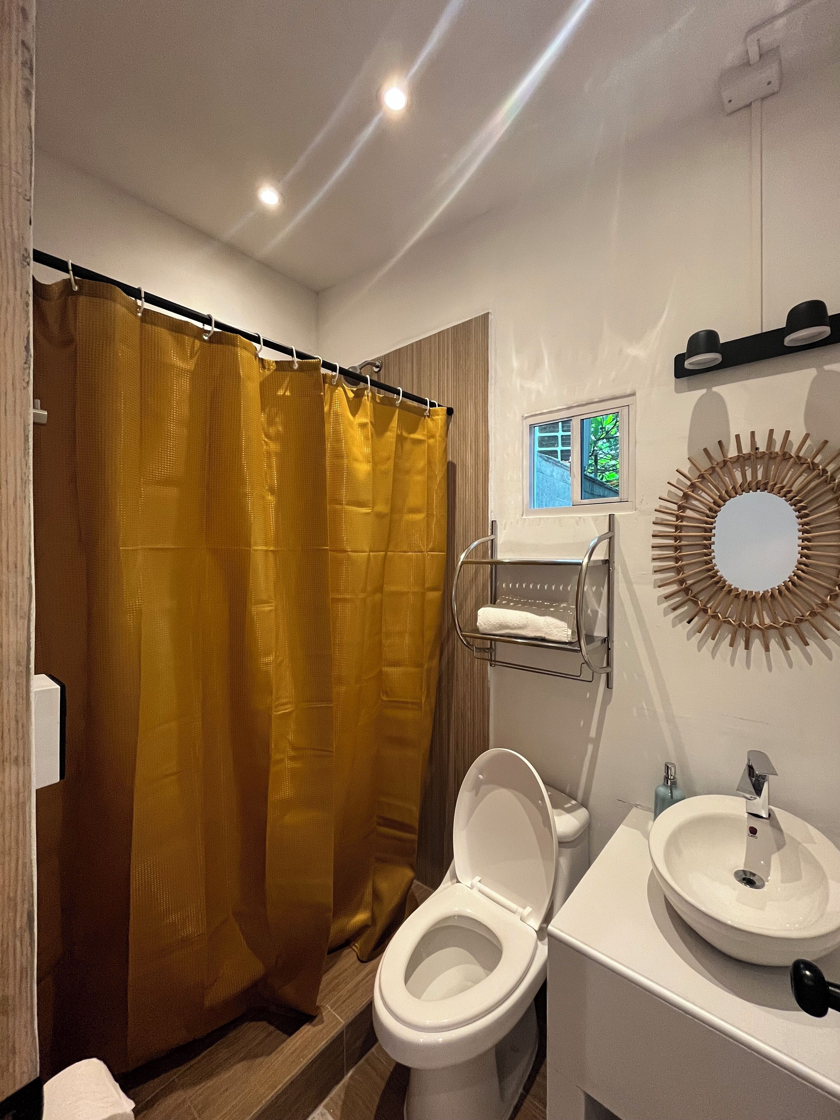 Un baño con inodoro blanco, lavabo, espejo y cortina de ducha.