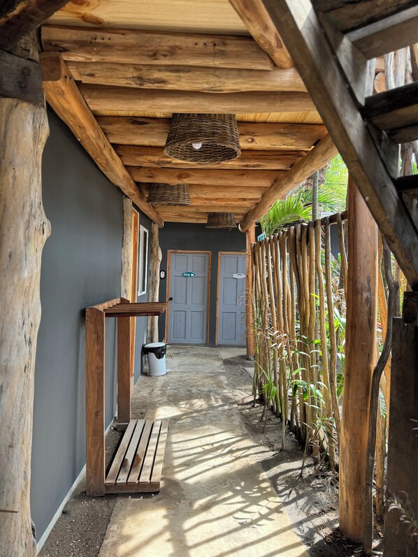 Un couloir en bois avec un banc, une poubelle et une porte portant l’inscription « Confortable ».
