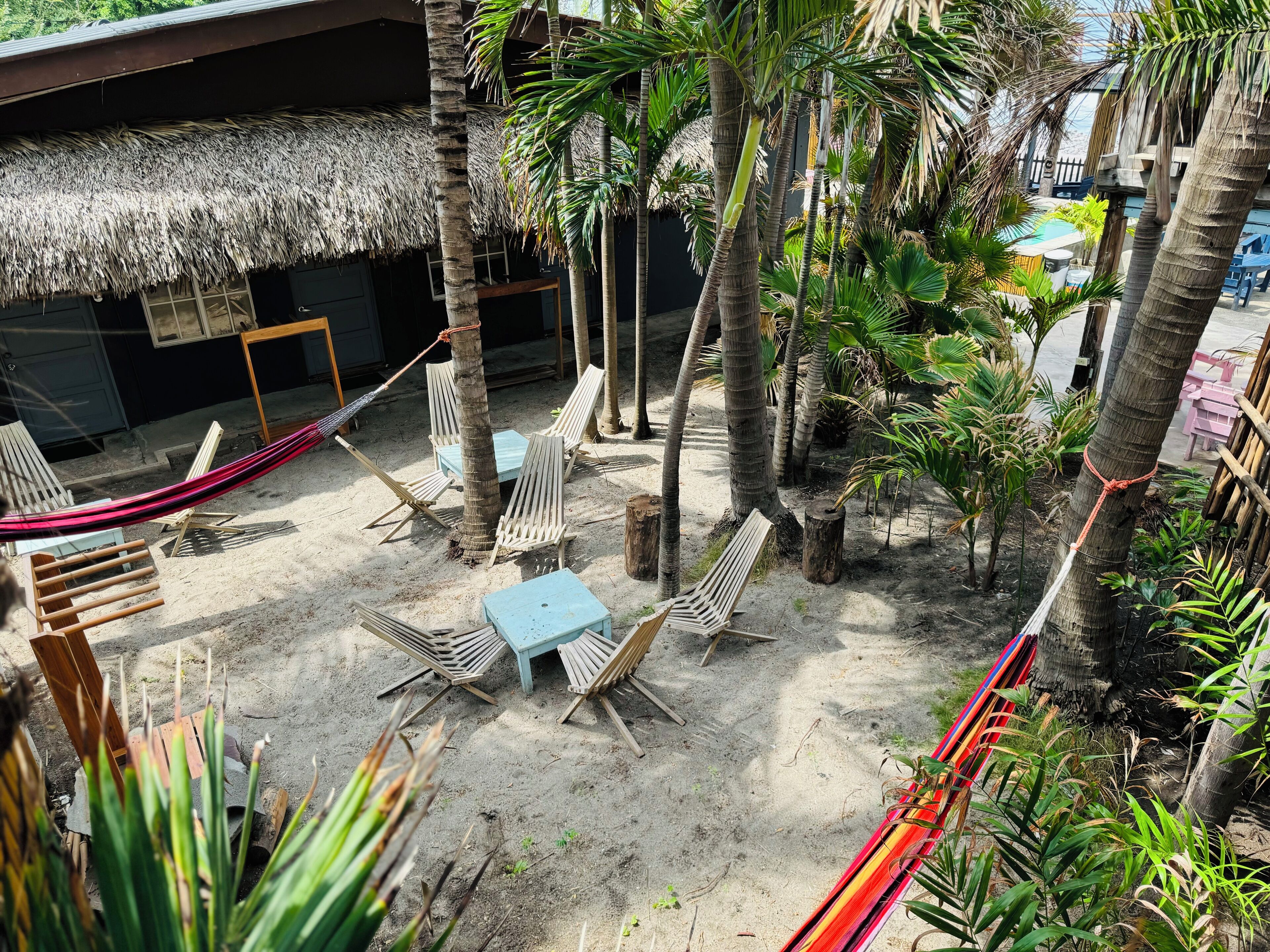 Estructura de techo de paja con asientos al aire libre y palmeras.
