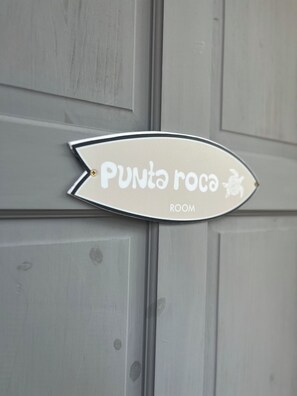 Une pancarte indiquant « Punta roca ROOM » sur un mur gris.