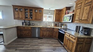 Une cuisine avec des meubles de rangement en bois, un lave-vaisselle, une cuisinière et une machine à café.