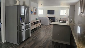 Une cuisine moderne dotée d’un réfrigérateur encastré, de meubles de rangement en bois et d’un coin repas avec une table et des chaises.