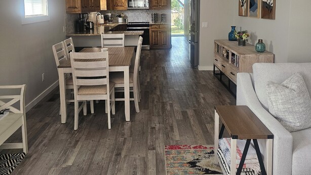 Une cuisine spacieuse dotée de meubles en bois, un coin repas avec une table et des chaises, et un salon avec un canapé et une table basse.