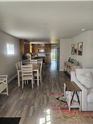 A spacious kitchen with wooden cabinets, a dining area with a table and chairs, and a living area with a sofa and a coffee table. - Modern Comfort in Downtown Victor  (Victor)