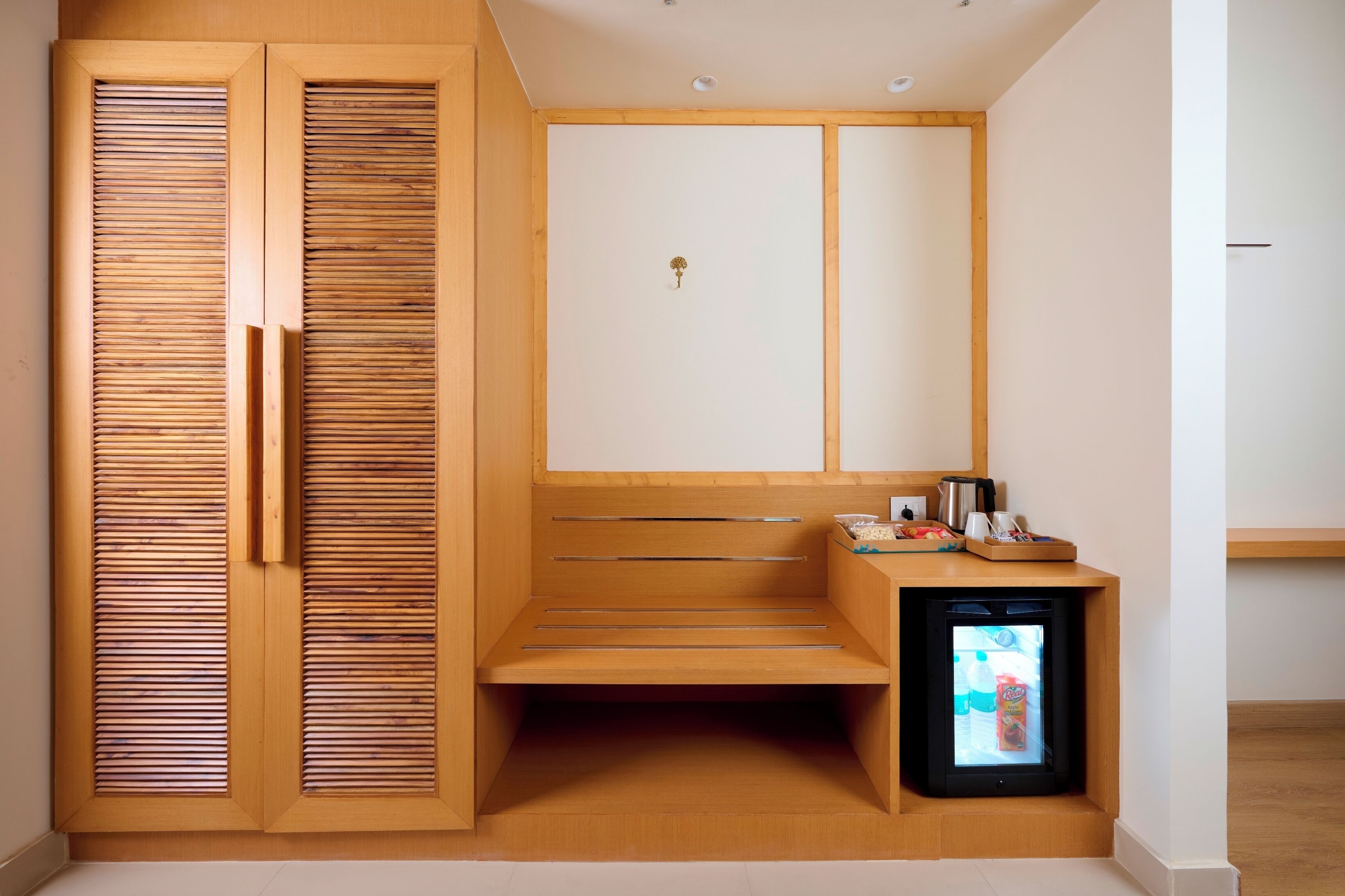 Un sauna avec des bancs en bois, une petite table avec une bouilloire et un réfrigérateur.