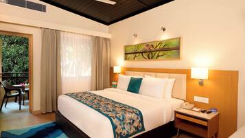 Habitación de hotel con cama, lámparas de noche, mesita de noche, un cuadro y vista a zonas verdes.