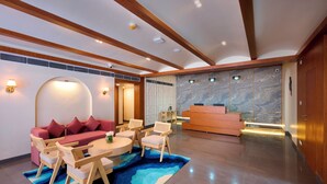 Un vestíbulo moderno con mostrador de recepción, un sofá rojo, sillas de madera y una alfombra azul.