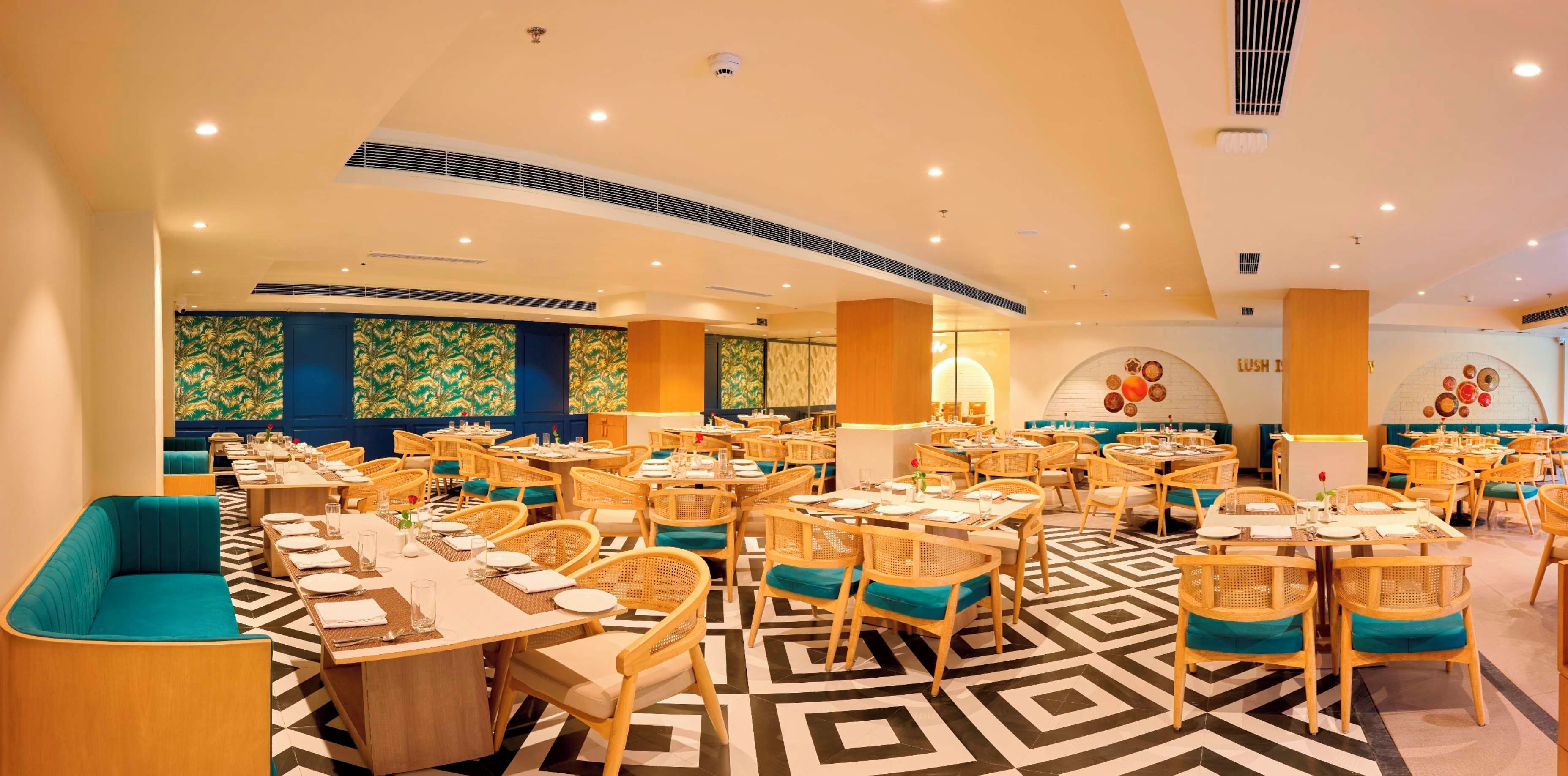 Un restaurante con varias mesas y sillas, un piso con diseño y paneles decorativos en la pared.