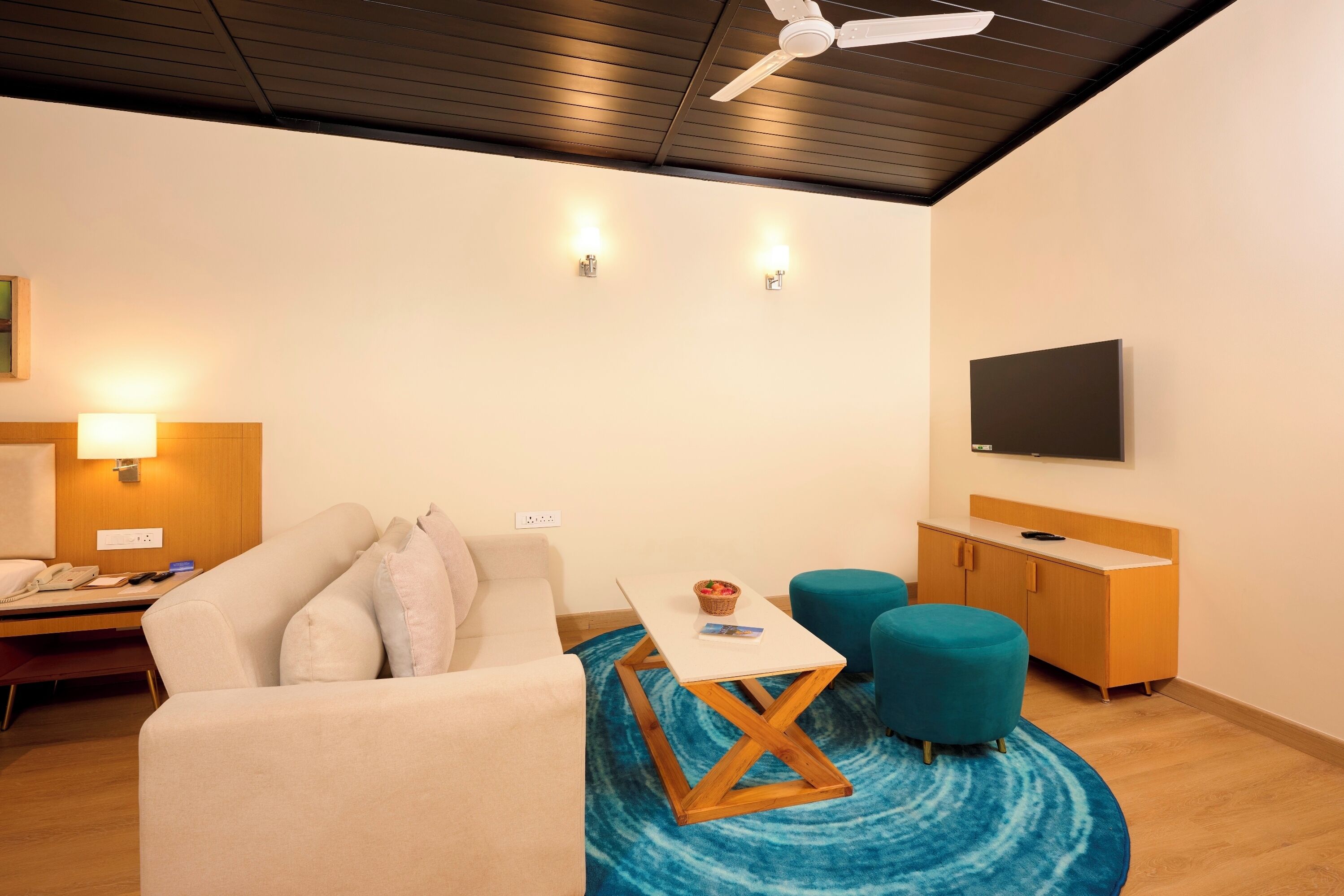 Una sala de estar moderna con un sofá, una mesa de centro, un televisor y un ventilador de techo.