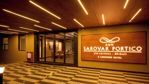 A hotel lobby with a checkered floor, a wooden signboard with the hotel name, and a modern ceiling design. - ABN Sarovar Portico Jim Corbett  (Ramnagar)
