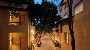 Un estrecho pasillo bien iluminado, con una puerta de madera al final, flanqueado por edificios con ventanas e iluminación exterior.