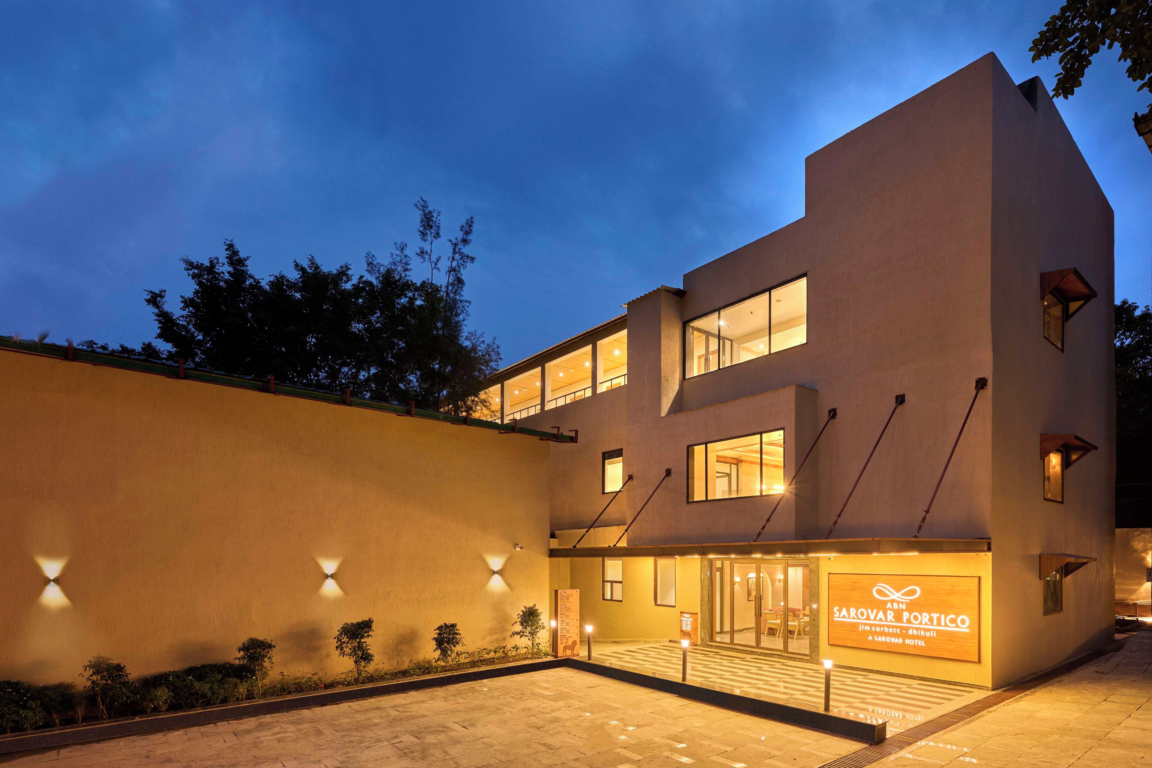 Un hôtel moderne à la façade sobre, doté de grandes fenêtres et d’une entrée bien éclairée.