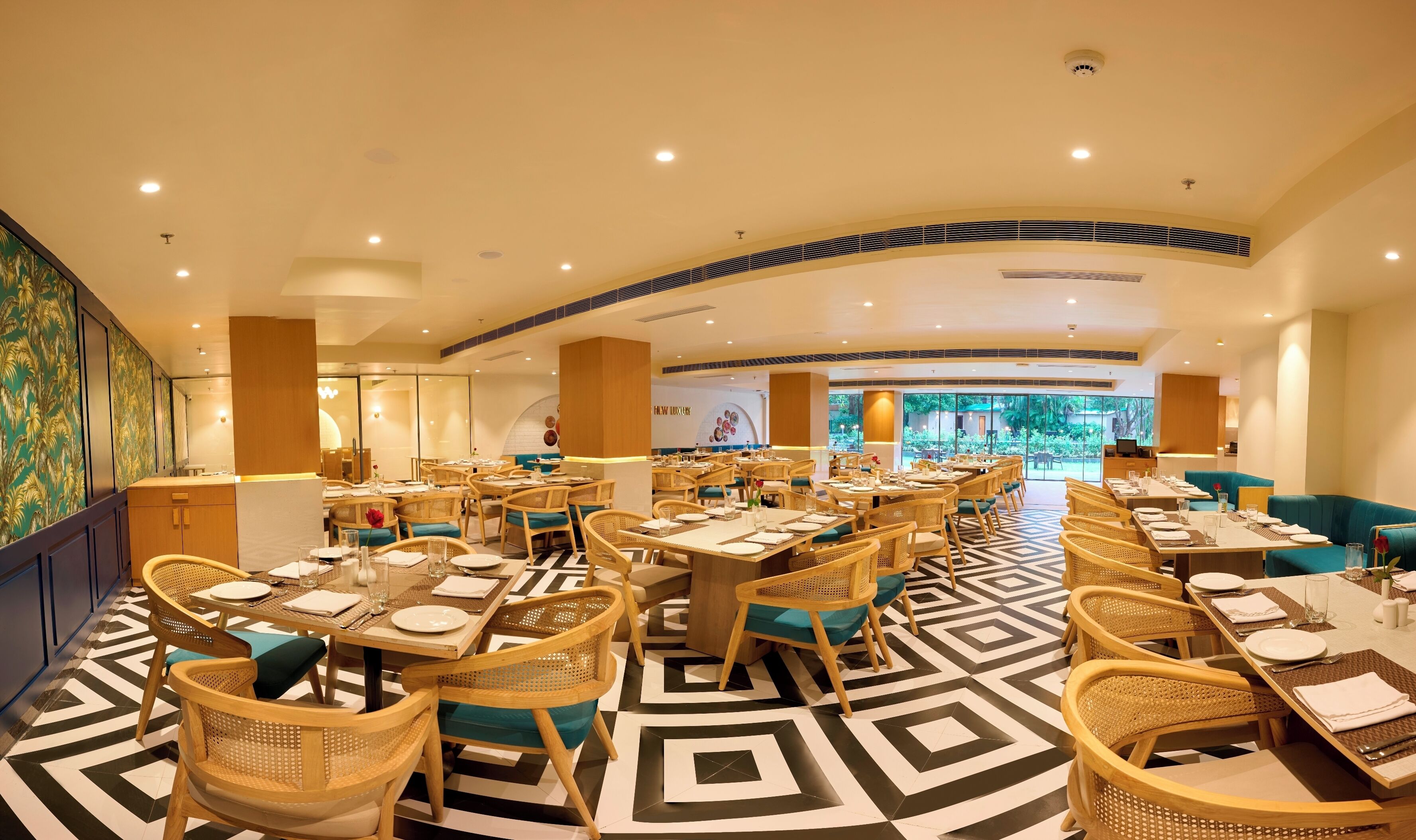 A spacious restaurant with high ceilings, modern lighting, and a geometric patterned floor.