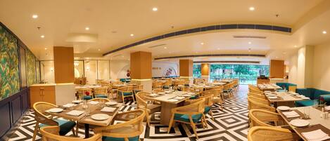 A spacious restaurant with high ceilings, modern lighting, and a geometric patterned floor.