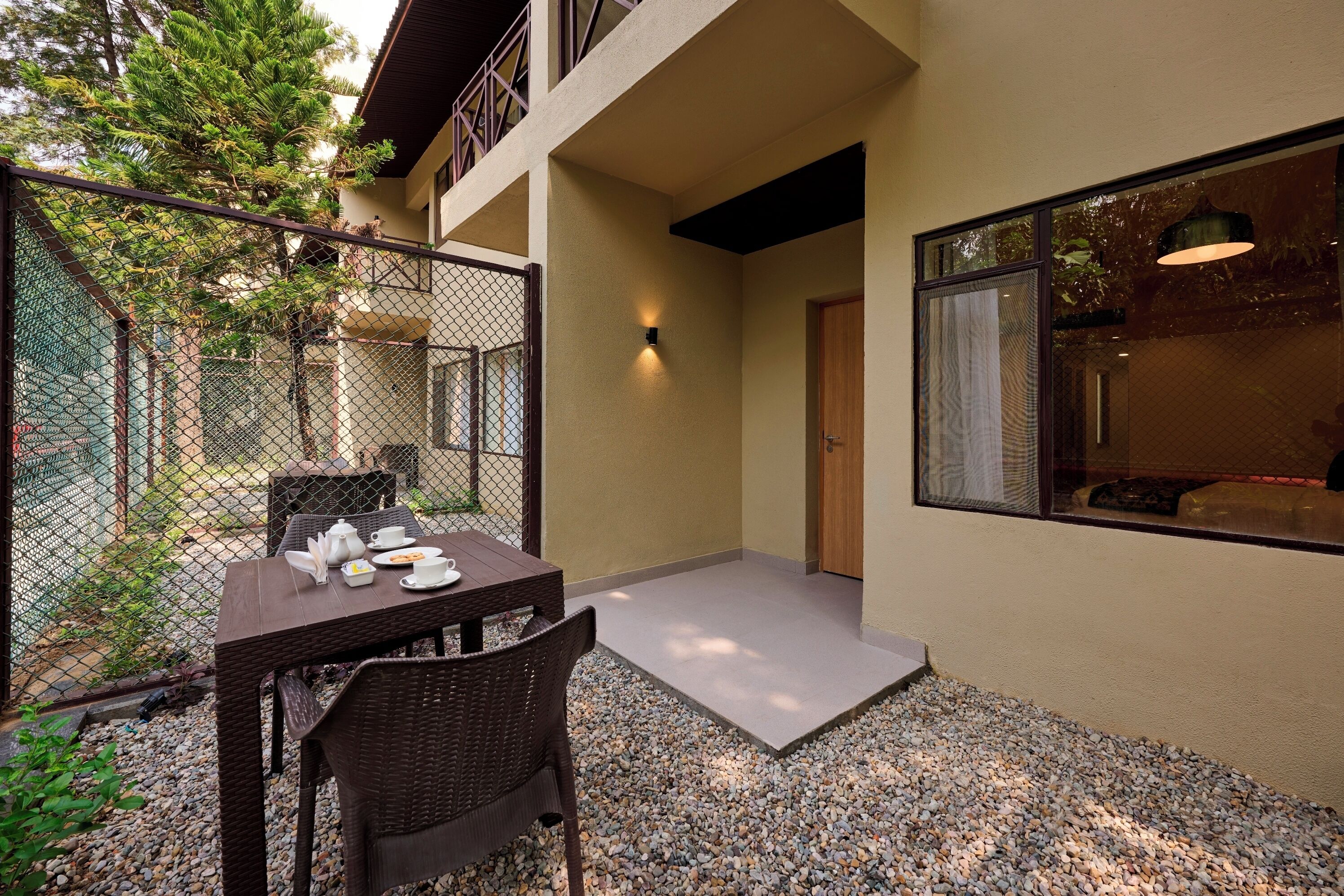 A dining area with a table and chairs, a small outdoor seating space, and a building entrance.