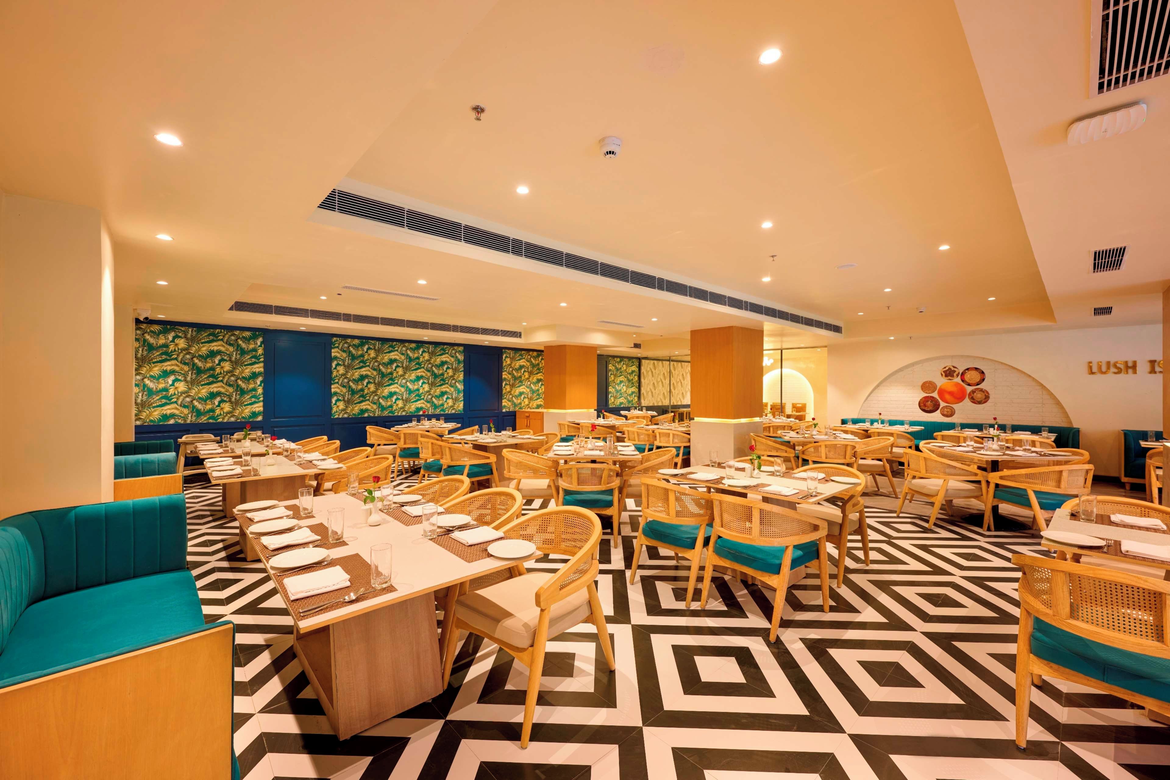 A restaurant with multiple tables and chairs, a patterned floor, and a wall with a circular design.