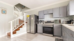 Uma cozinha moderna com armários cinza, eletrodomésticos de aço inoxidável e painel de azulejos.