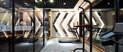 A modern gym with cardio equipment, mirrored walls, and a chevron-patterned wall design.