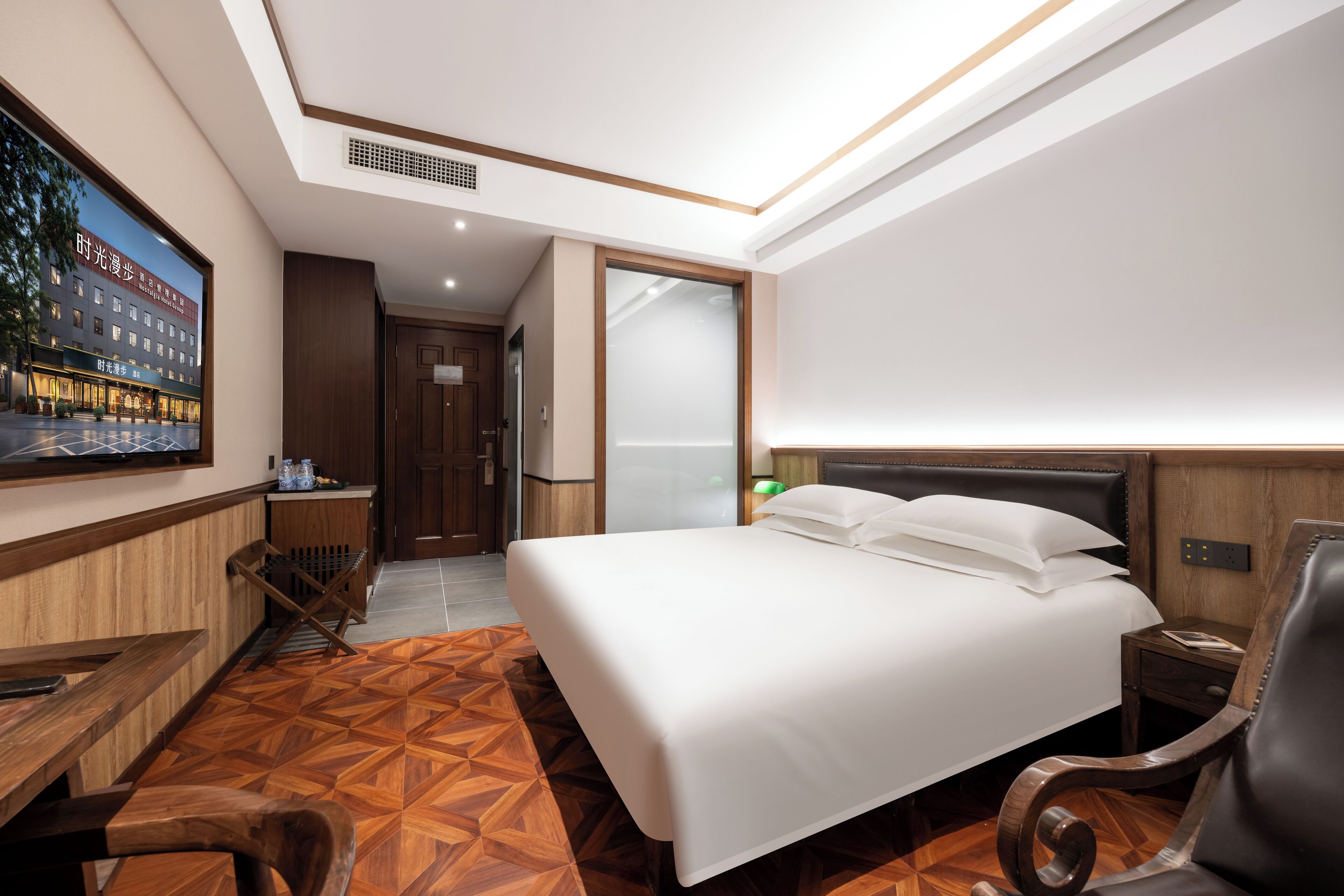 A hotel room with a large bed, wooden desk, and a view of the hotel building.