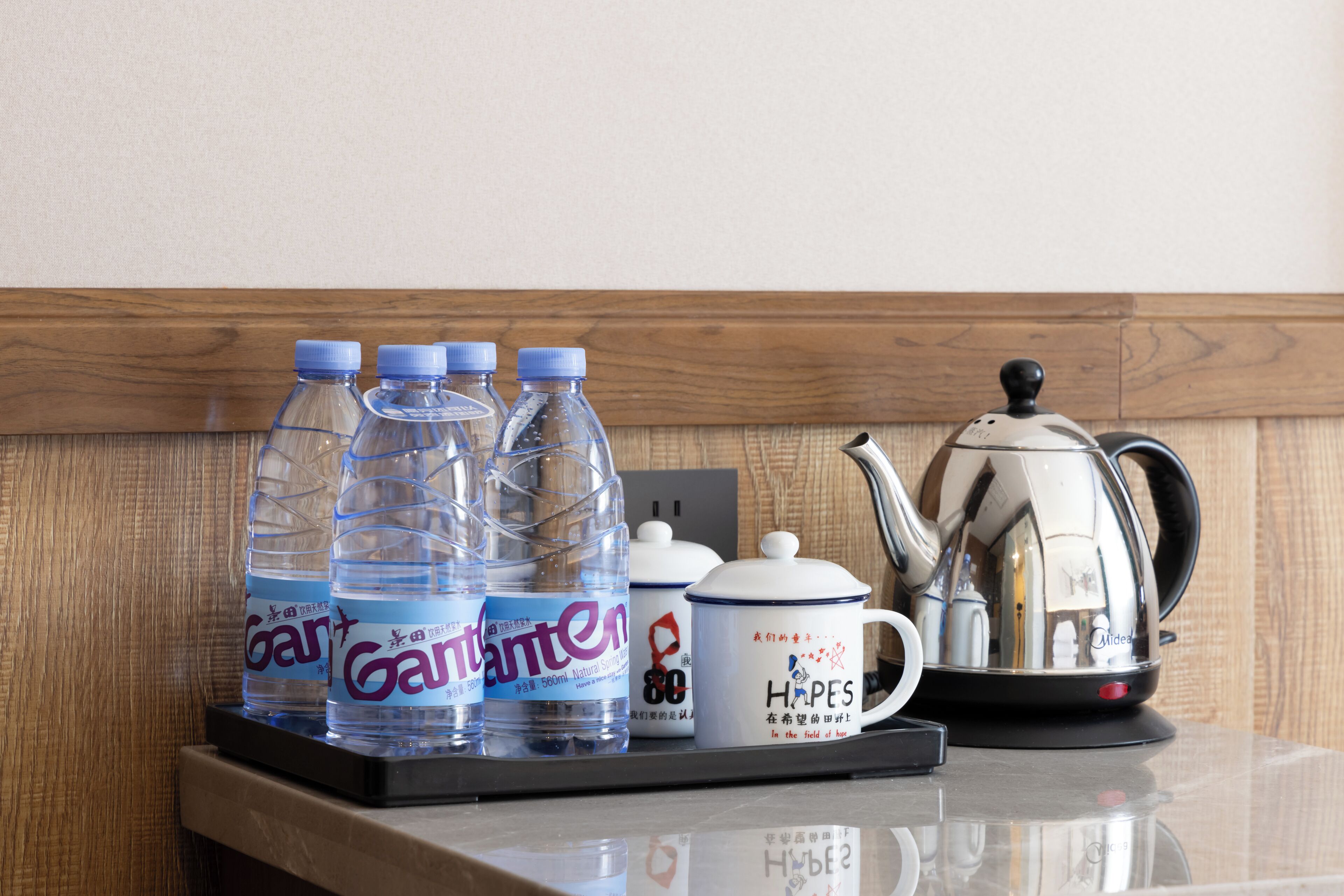 A tray with water bottles, a teapot, and a mug on a wooden countertop.