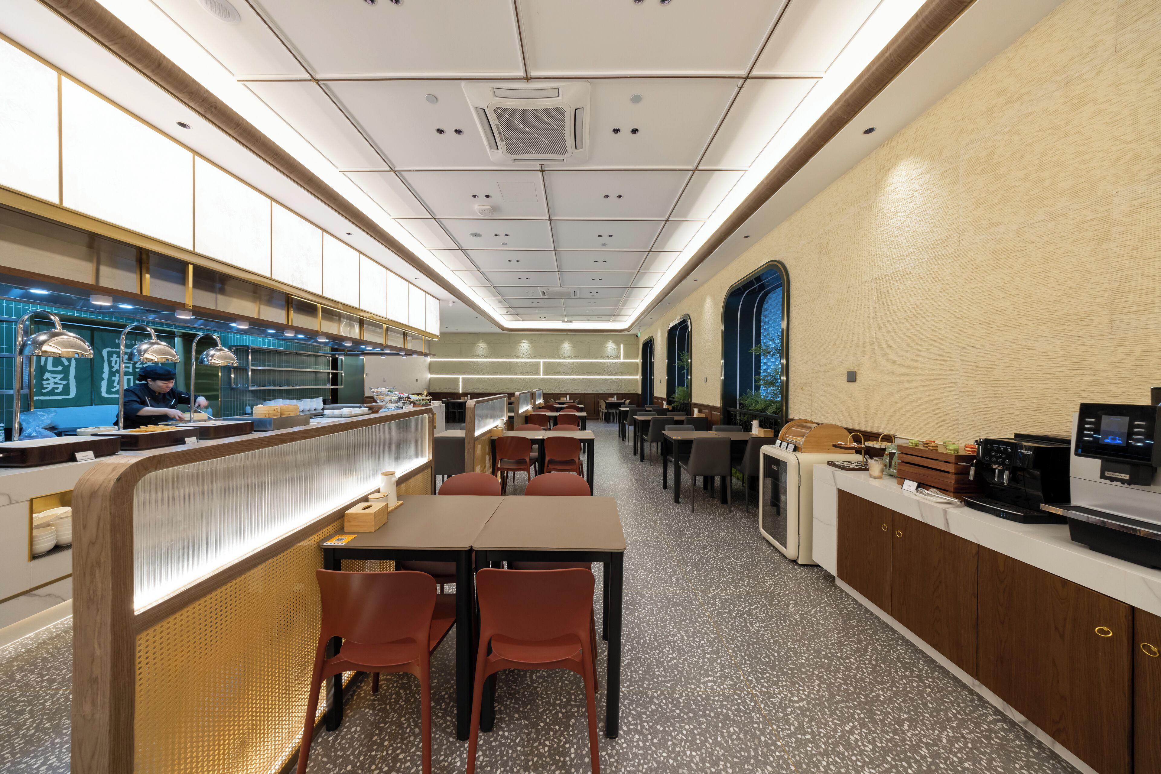 Un restaurant moderne doté d’un long comptoir, d’un espace salon et offrant une vue sur l’extérieur grâce à une grande fenêtre.